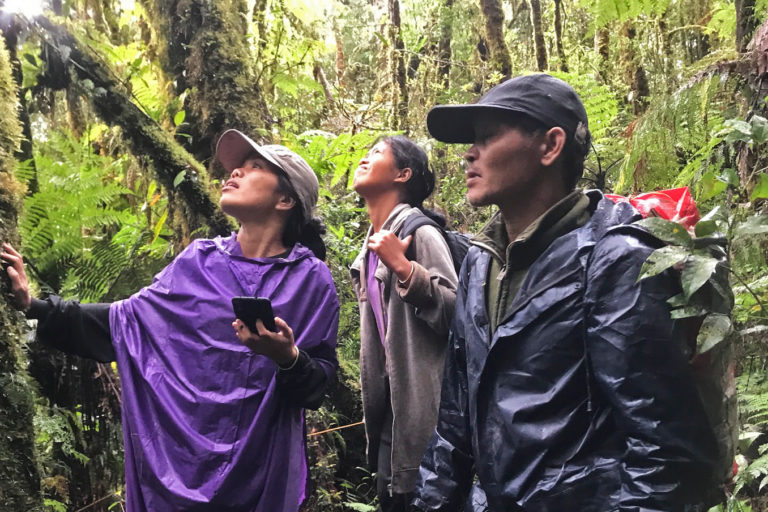 Michellejean with a GPS device with elders in the forest.