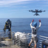 A marine researcher launching a drone for ocean color surveys