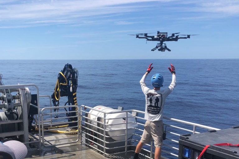 A marine researcher launching a drone for ocean color surveys