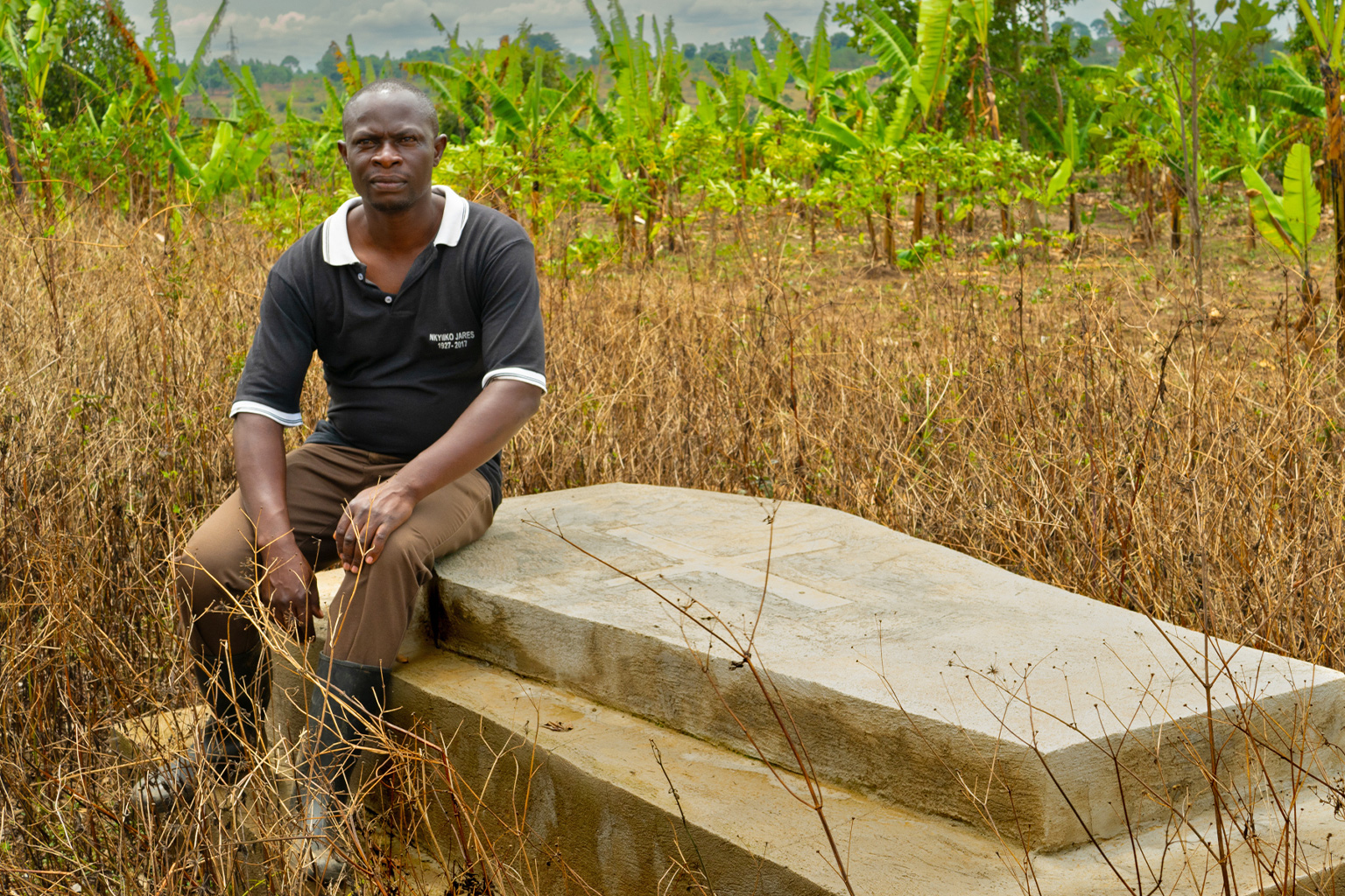 Robert Lule, with grave, Greater Massaka Area, Uganda.