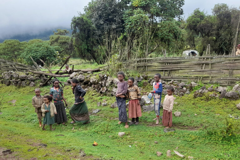 Small children from Rira village stand by the roadside near their humble home.