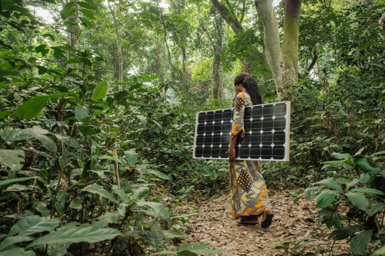Woman carrying a solar pannel near Yangambi, DRC.